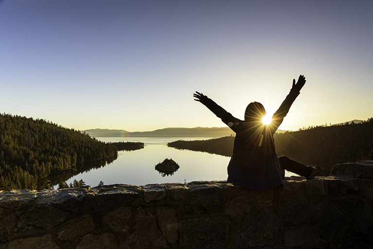 A woman embracing a  beautiful sunrise at Emerald Lake, California