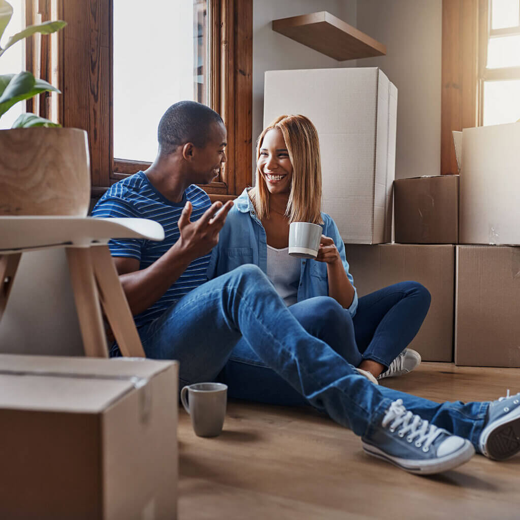 Happy couple on the ground with moving boxes around